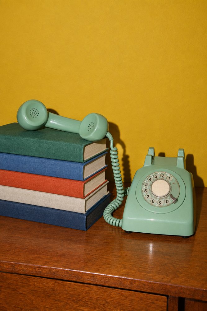 Home Page (new) 6 A vintage rotary telephone off the hook on a stack of books